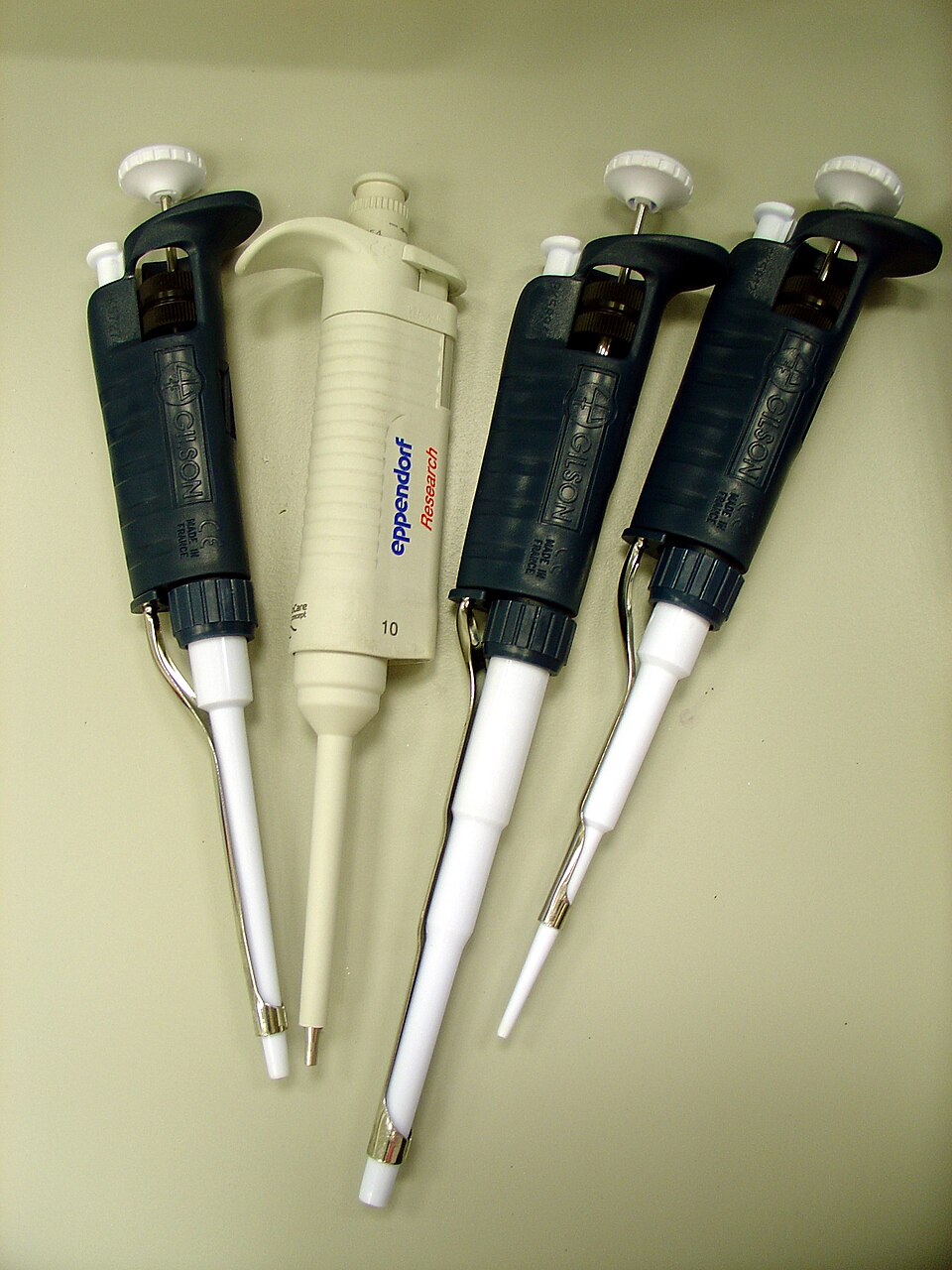 Four adjustable micropipettes used for precise liquid measurement in laboratory training
