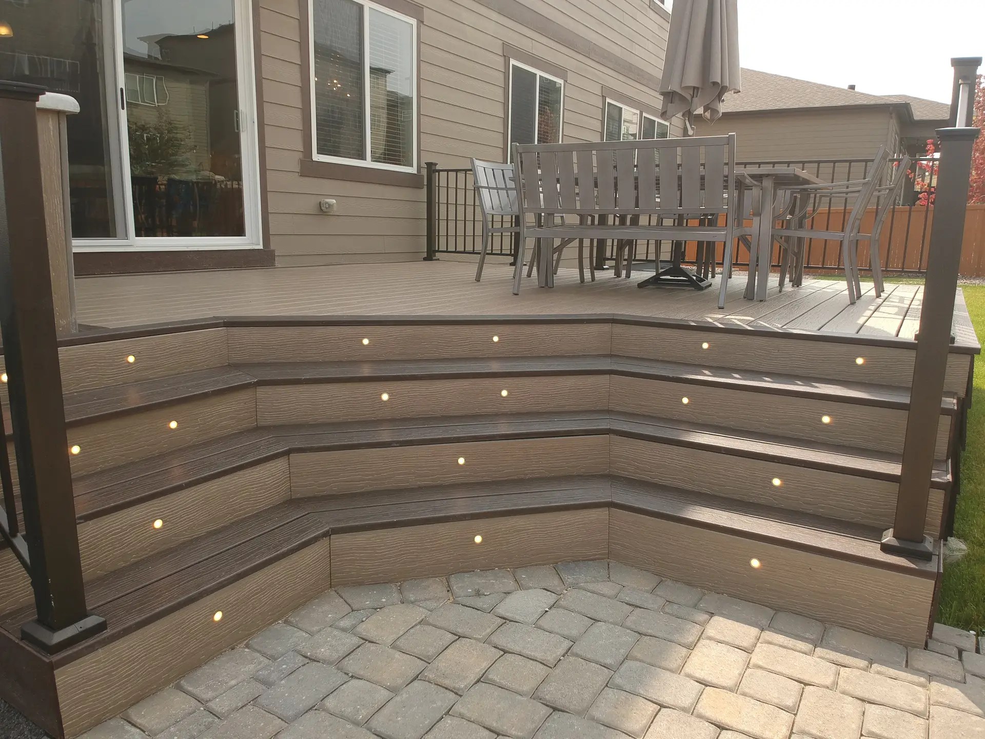 Deck stairs with button lights leading to paver patio