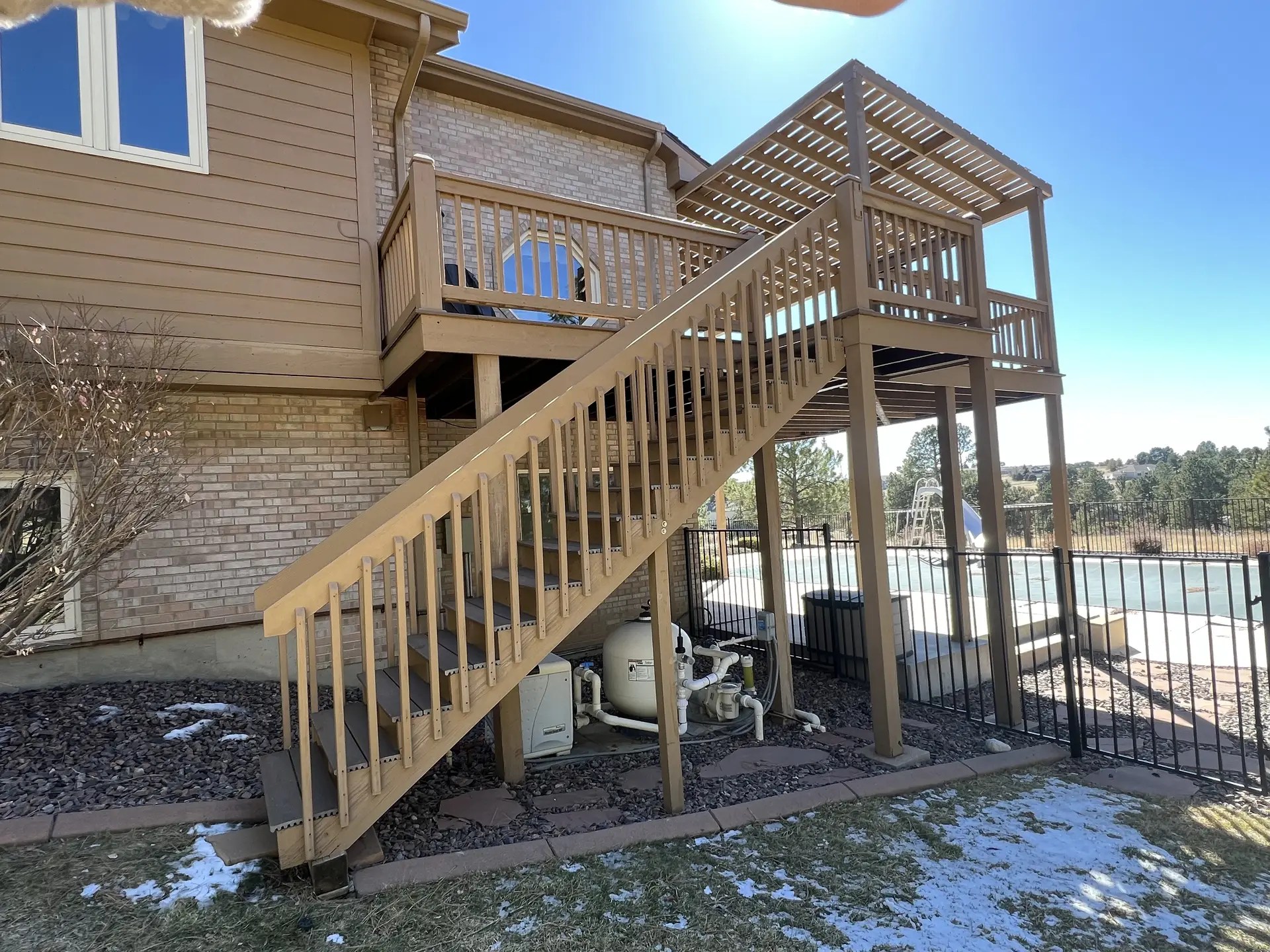 View from the ground of a second story wood deck and pergola. Side view