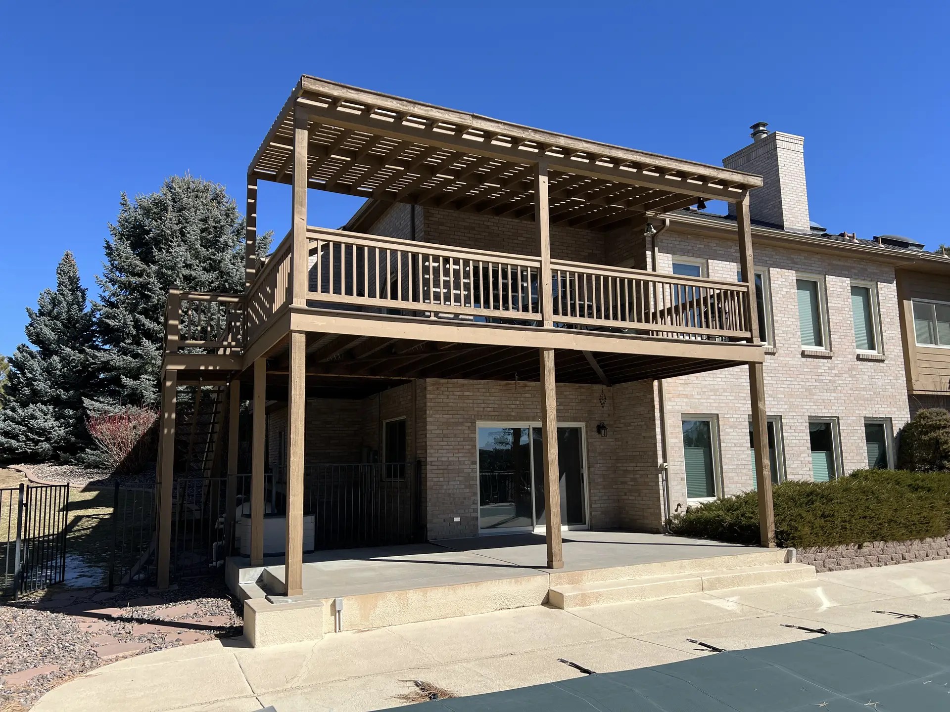 View from the ground of a second story wood deck and pergola. Front view.