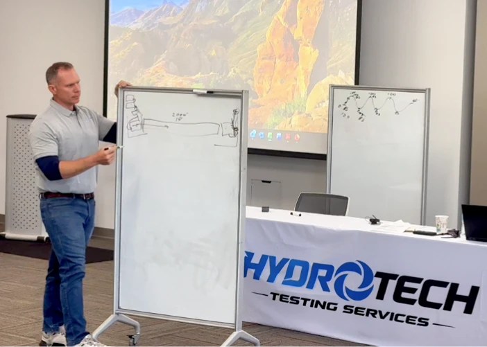 Instructor demonstrating hydrostatic testing concepts on whiteboard