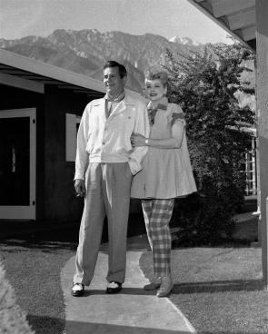 Beloved Lucille Ball & her famous husband Desi Arnaz stand outside their Palm Springs home back in 1953.