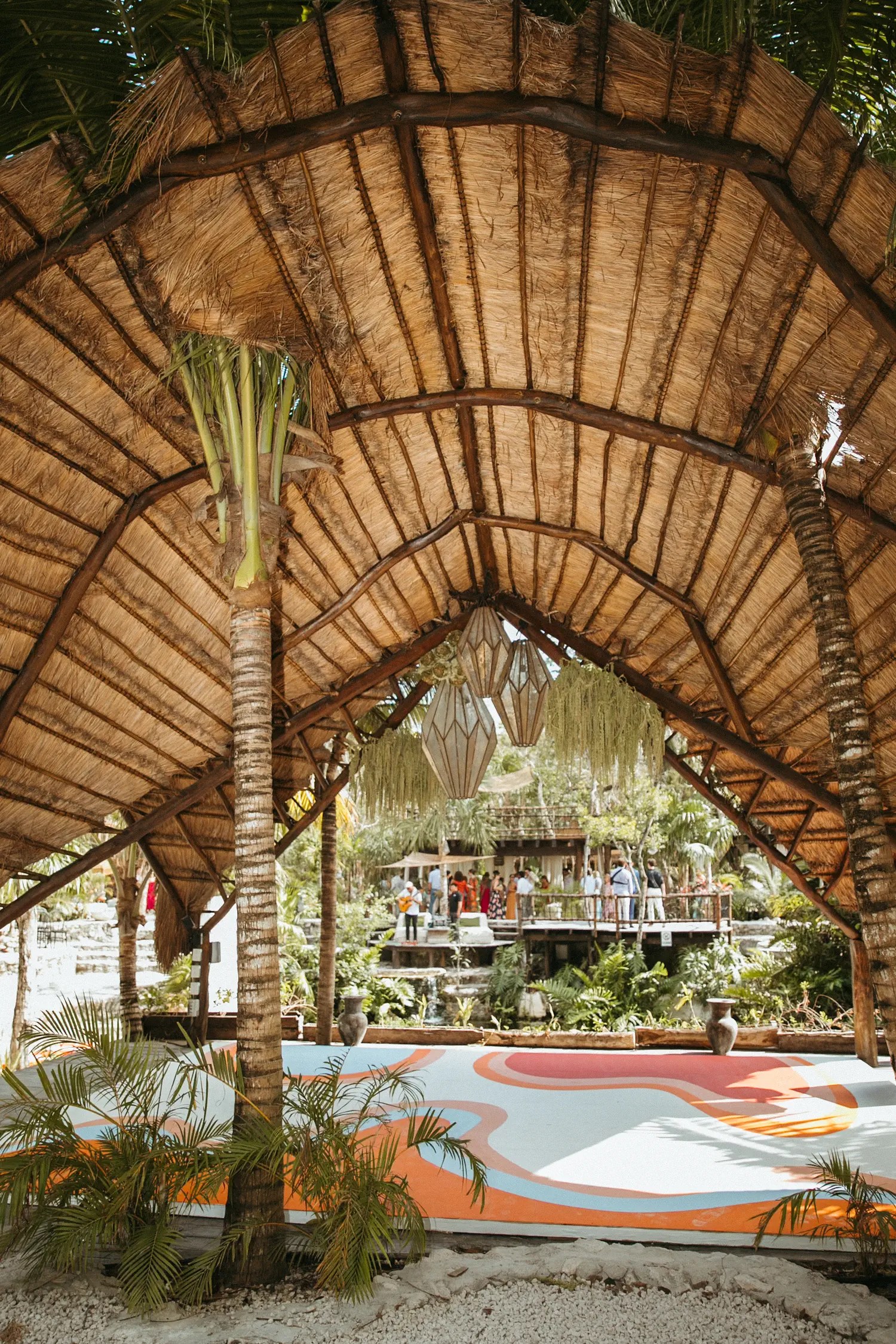 See through a dome-roofed palapa on a dance floor painted with psychedelic swirls with guests on deck.