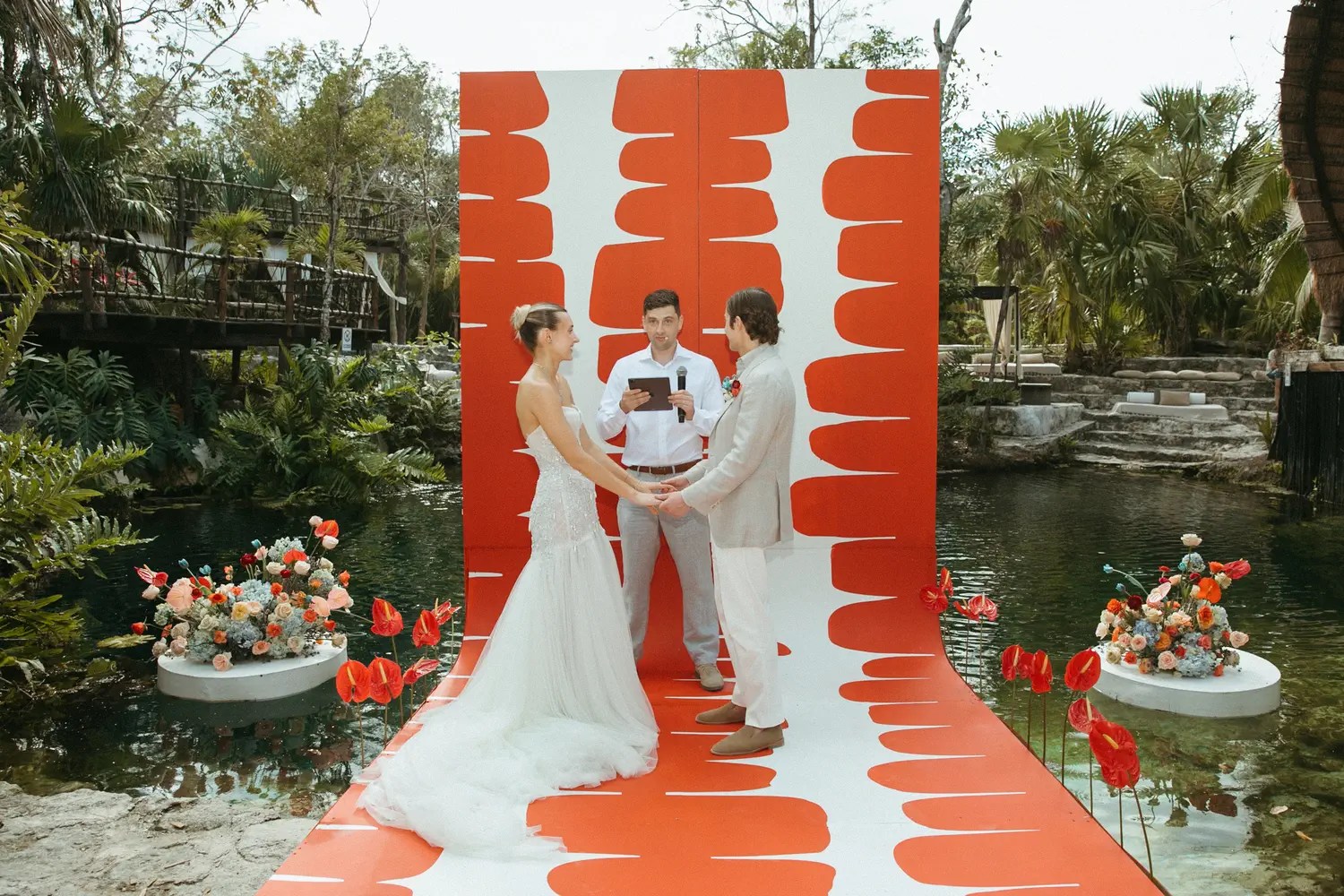 An officer holding hands at the altar of Laura and Stephen Sinnott and patterned runners with floral pedestals.