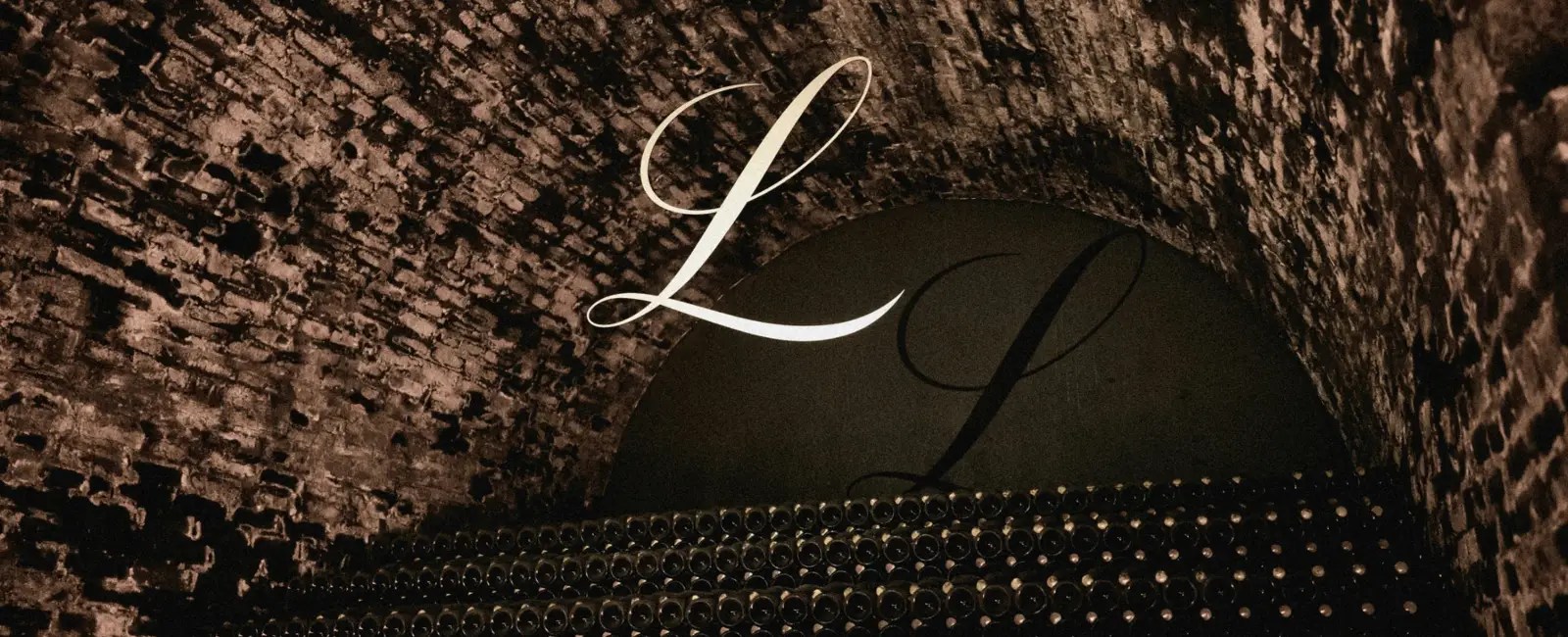 Image of champagne bottles in a cellar with a decorative L hanging above it