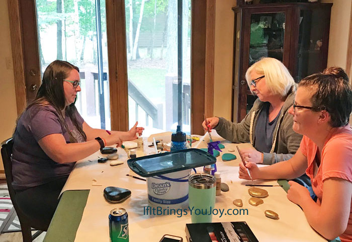 People painting kindness rocks at a table.