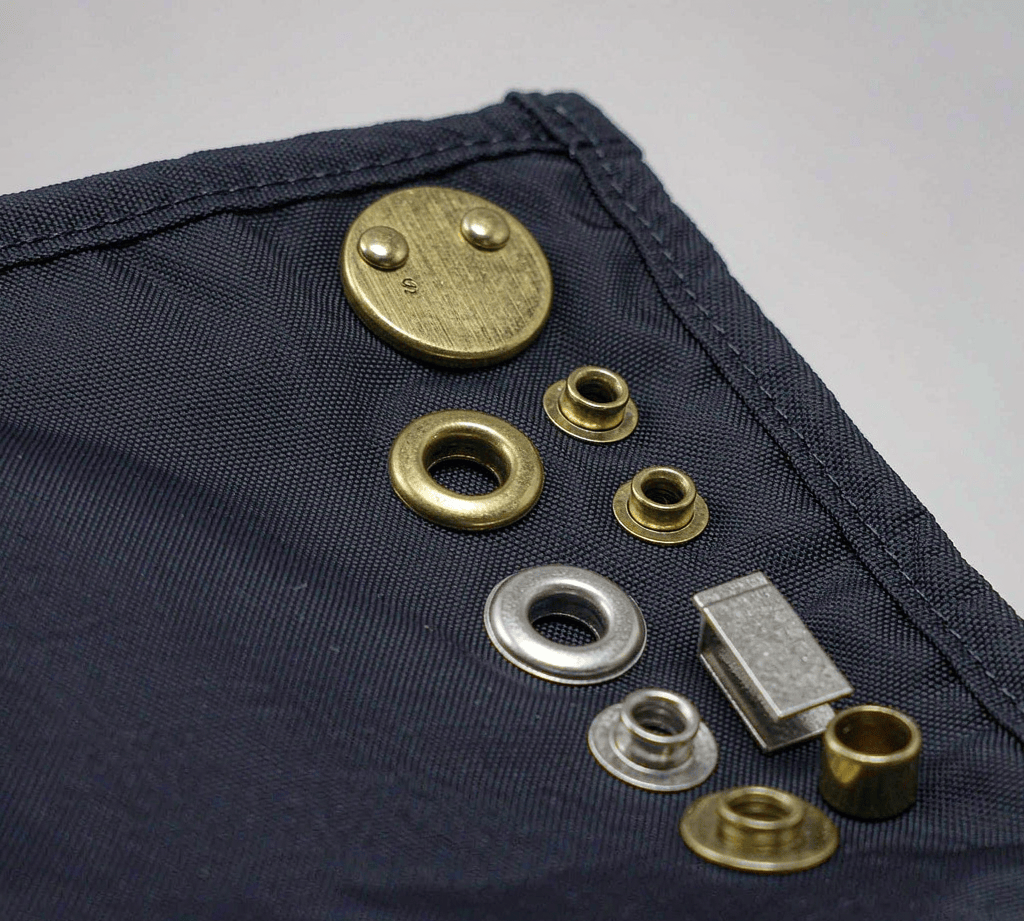 Close-up of brass and nickel metal grommets and eyelets set into navy backpack fabric