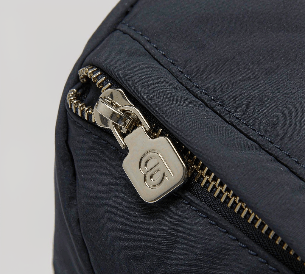 Custom metal zipper pull tab on a navy bag fabric sample
