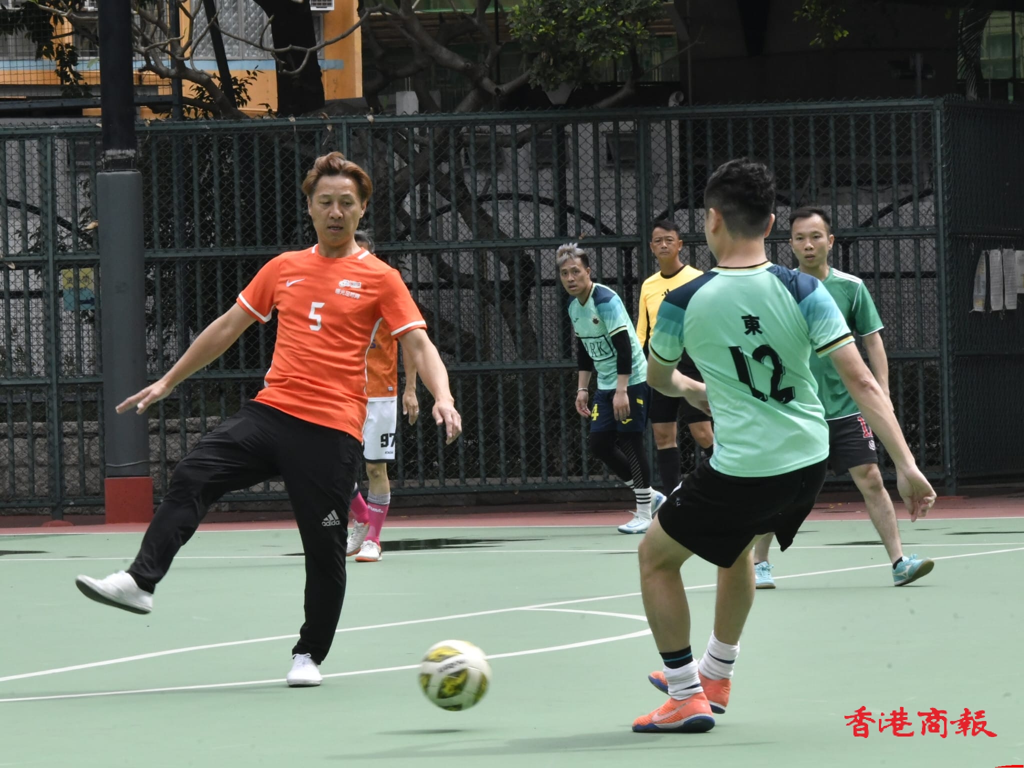 球員在深水埗硬地足球場運球競技，展現自信與拼搏精神。