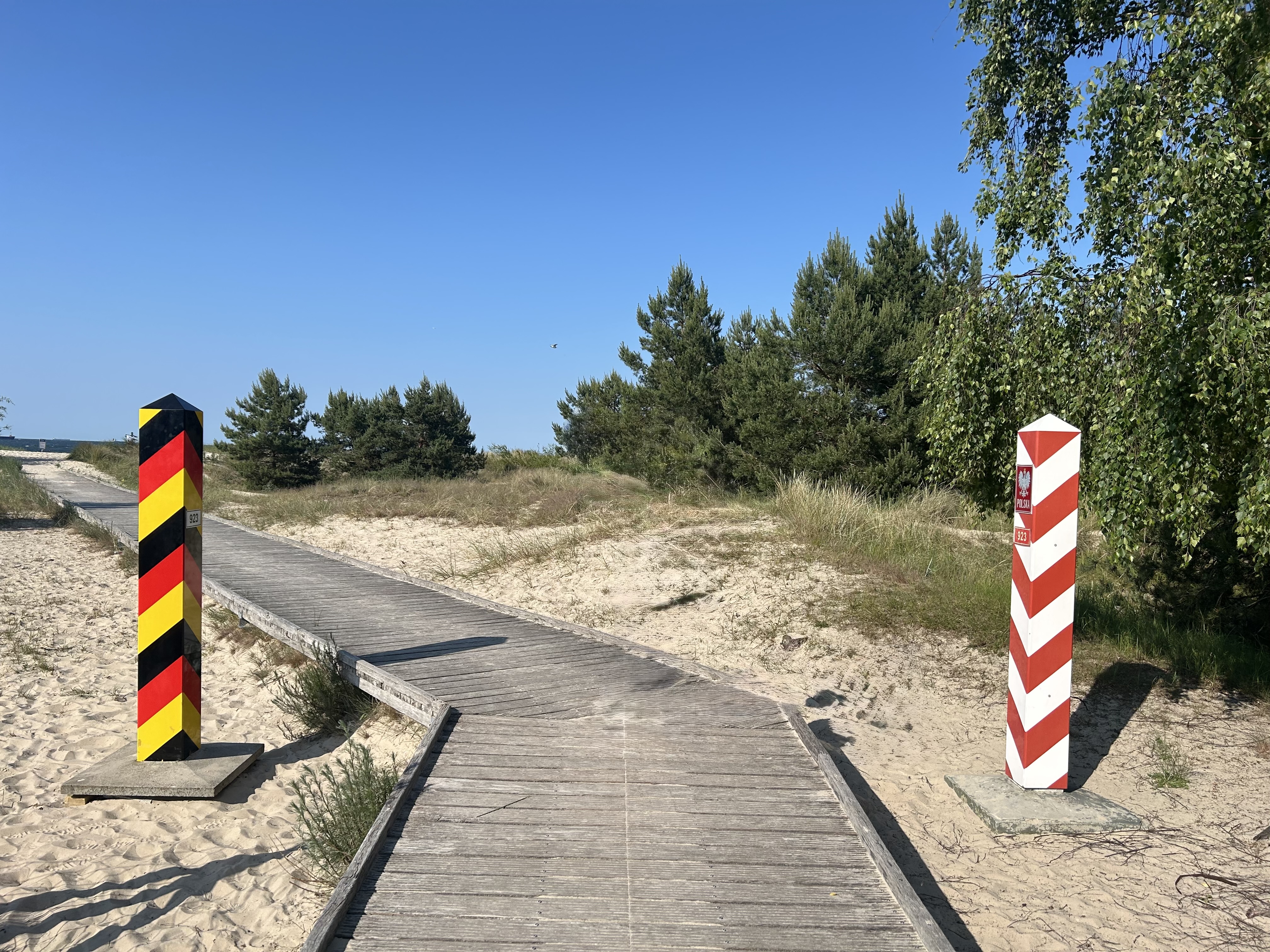 Deutsche und polnische Grenzpfähle an einem hölzernen Steg am Strand zwischen Swinemünde und Ahlbeck