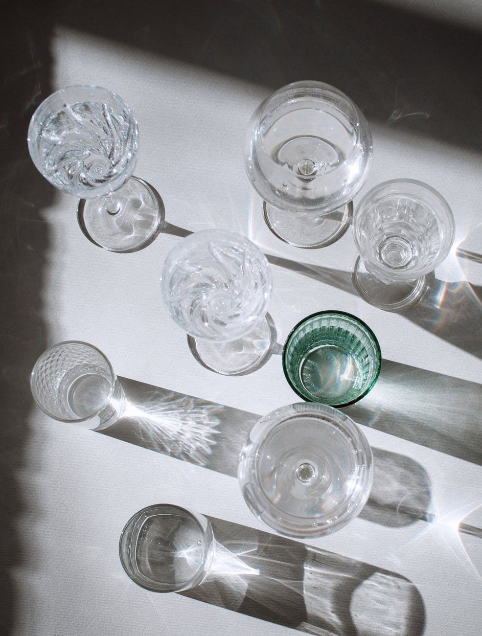 assorted glasses on shiny surface with shadows in sunlight