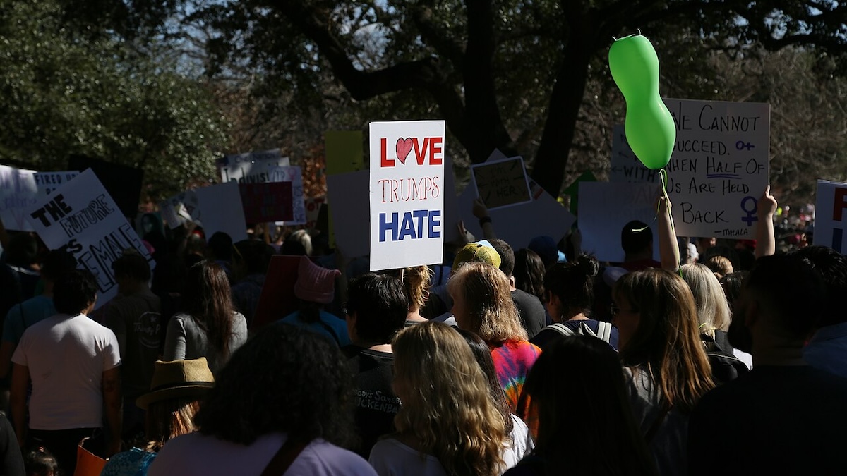 A protestor holds up a sign saying Love Trumps Hate at a protest.