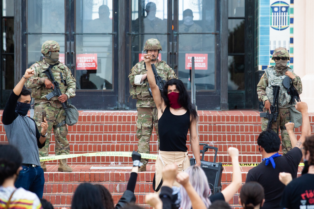 A group of protesters ends their march through downtown San Diego with a moment of silence for eight minutes and 46 seconds to mark the amount of time a Minneapolis police officer used his knee to hold George Floyd to the ground, June 6, 2020. California National Guard troops and San Diego County sheriff’s deputies look on from the County Administration Building.