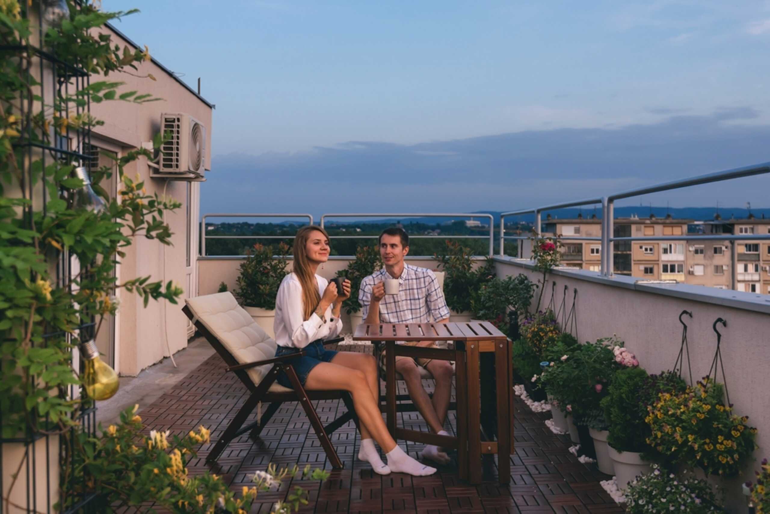 Două persoane stând pe balcon la apus