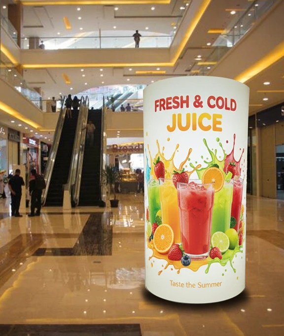 Mall interior with a cylindrical stand showing fresh cold juice drinks
