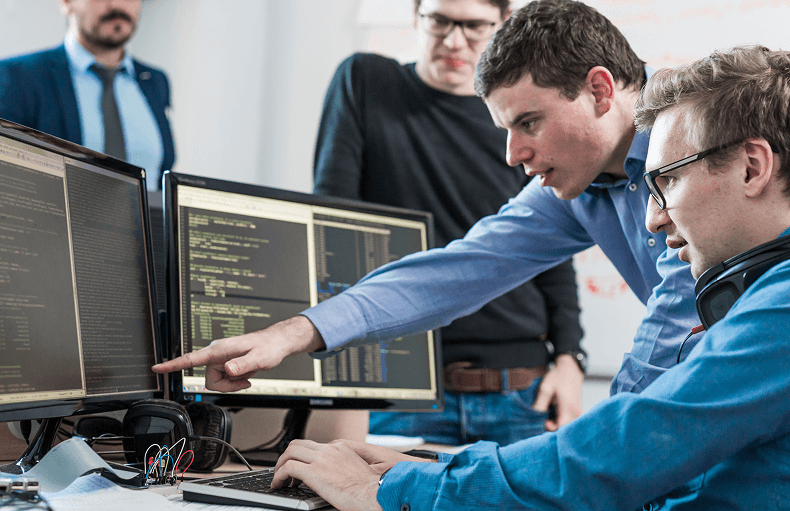 Two men are engaged in computer work at a desk, demonstrating teamwork and concentration in a shared workspace.