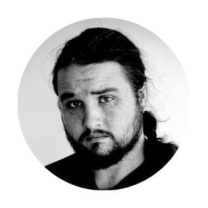 A black-and-white circular portrait of author Trey Stone, showing him with a serious expression, a beard, and long hair pulled back.