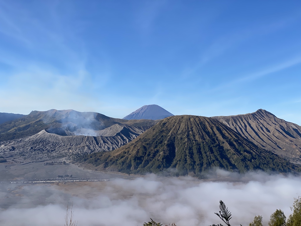Mt Bromo (on the left); other volcanos on the right or in the background. The flat Tengger caldera is shown in the foreground