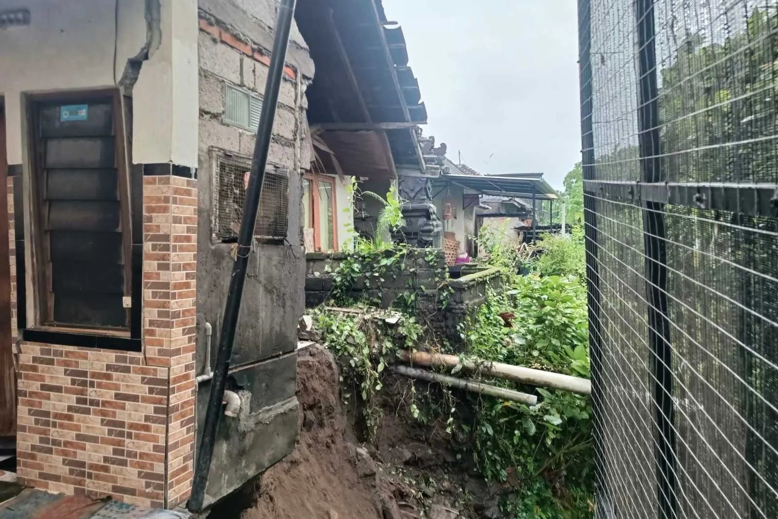 Petugas kepolisian mengecek lokasi Tanah Longsor di Desa Lebih yang menyebabkan dapur warga jebol.