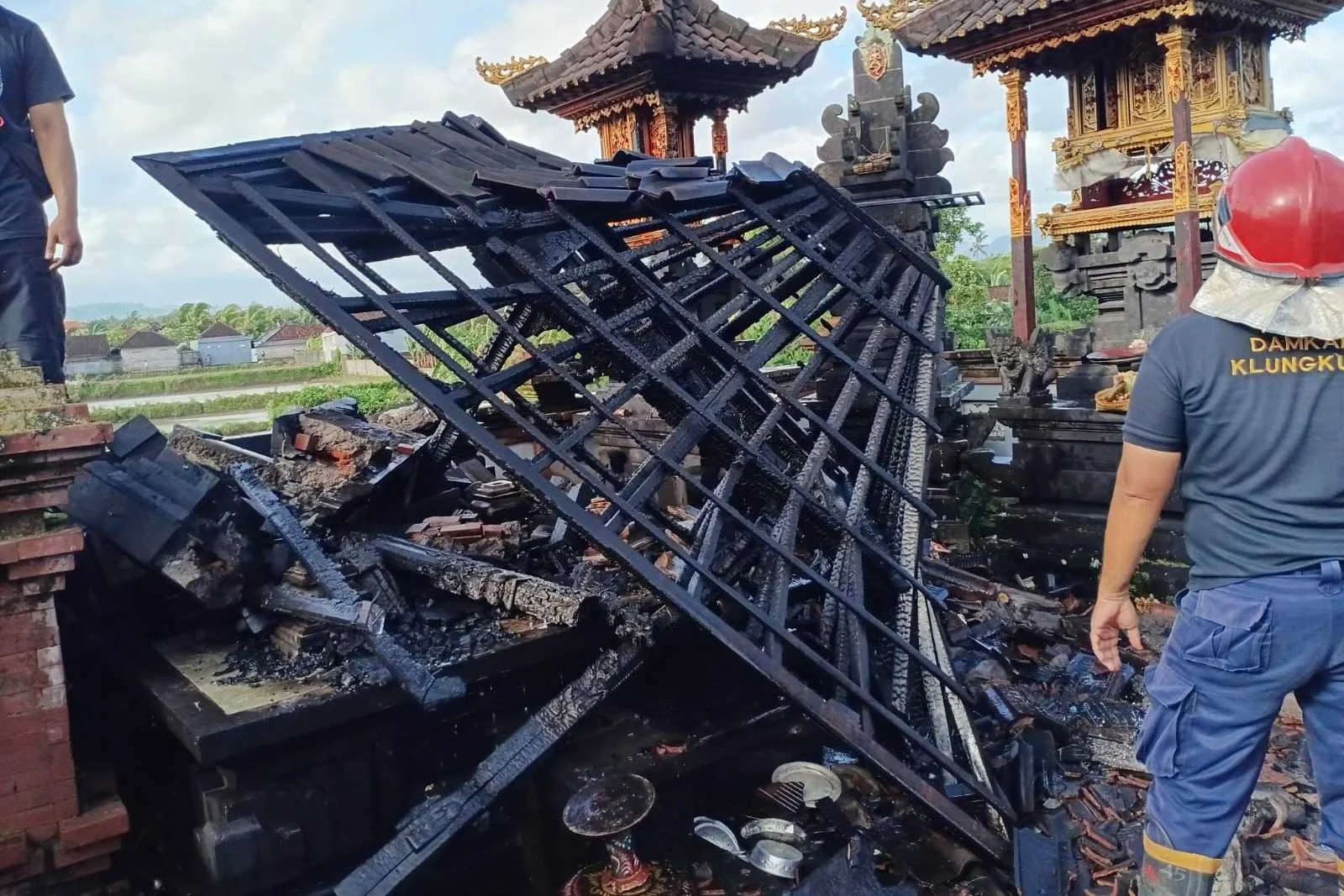 Petugas Damkar Klungkung saat melakukan pendinginan di piyasan merajan yang terbakar di Banjarangkan.