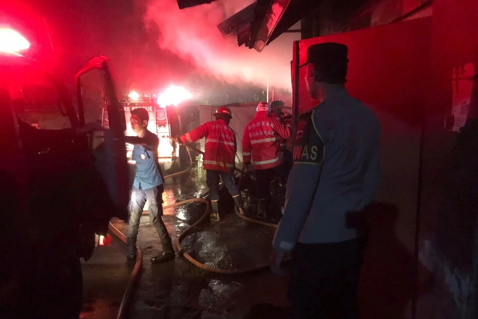 Petugas pemadam kebakaran dan personel Polsek Sukawati saat memadamkan api di kios yang terbakar di Batubulan.