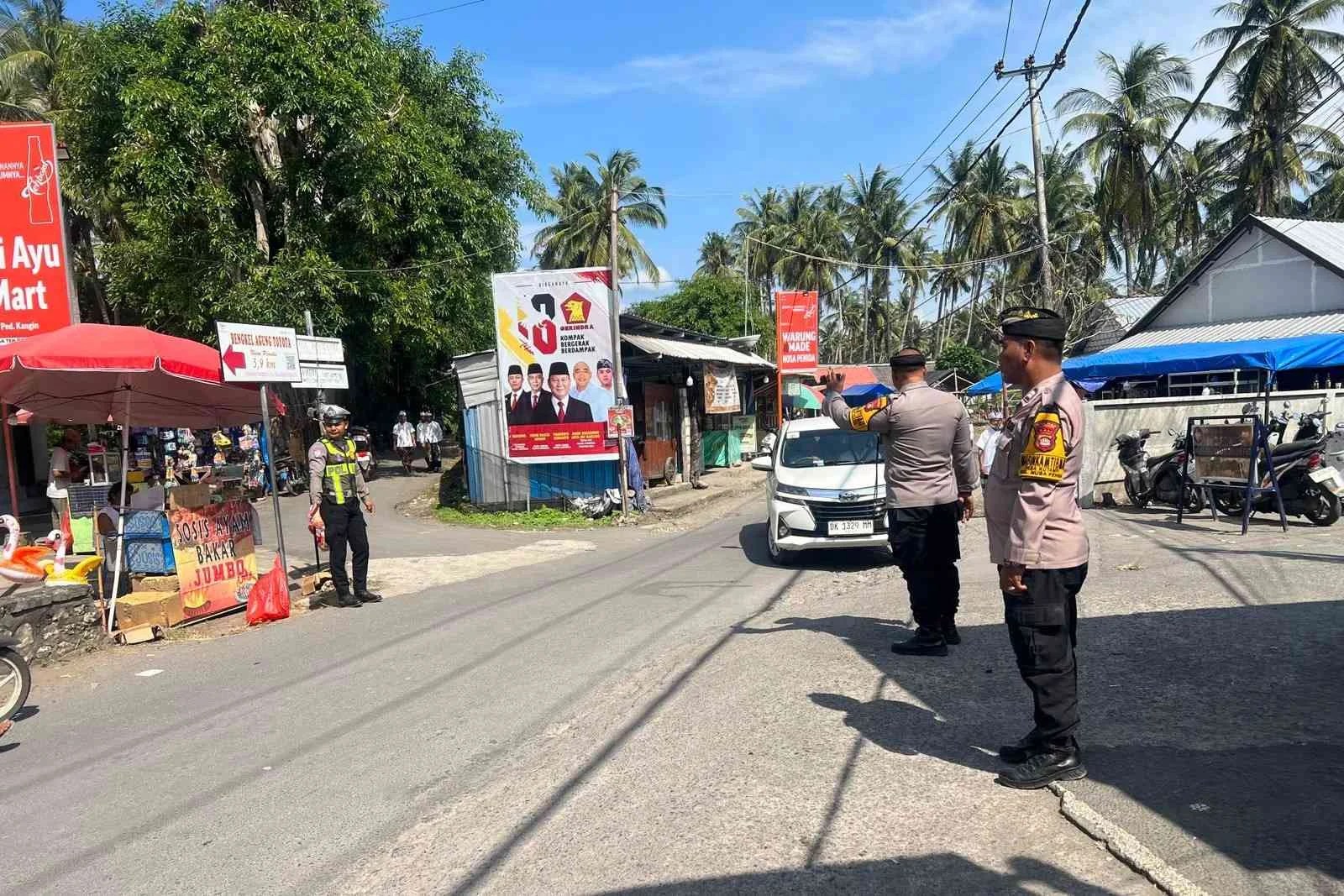 Personel Polsek Nusa Penida saat membantu penyeberangan pemedek dan mengatur arus lalu lintas di depan Pura Penataran Ped.