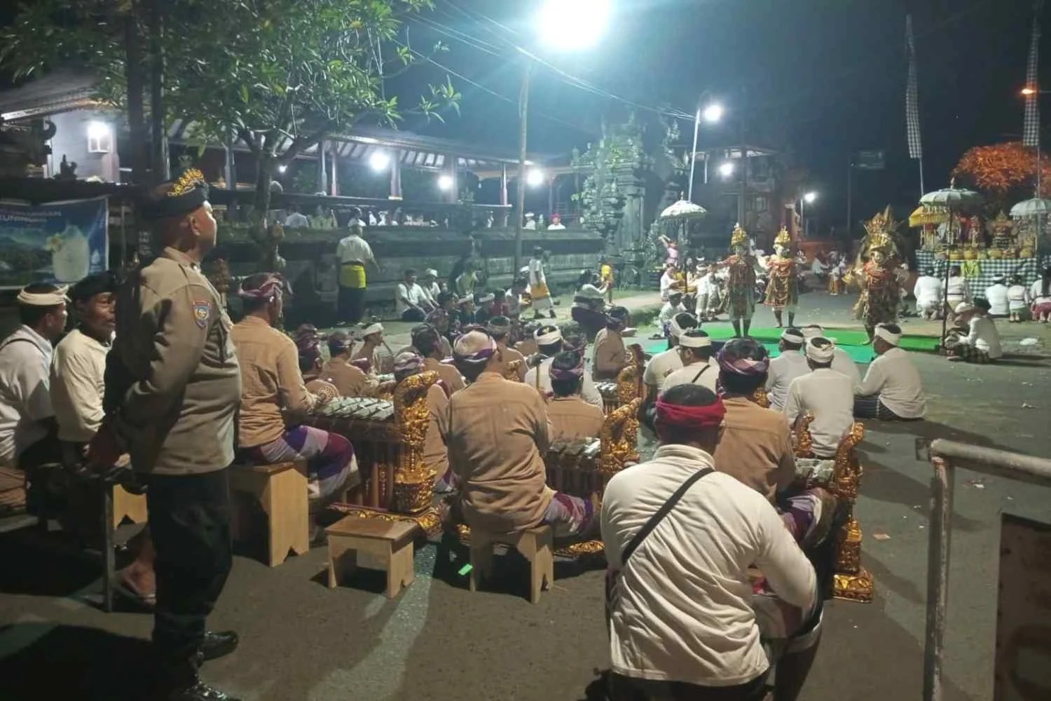 Bhabinkamtibmas Desa Gunaksa Aiptu I Nyoman Budiasa saat mengawal prosesi adat Napak Pertiwi di perempatan Desa Gunaksa pada dini hari.