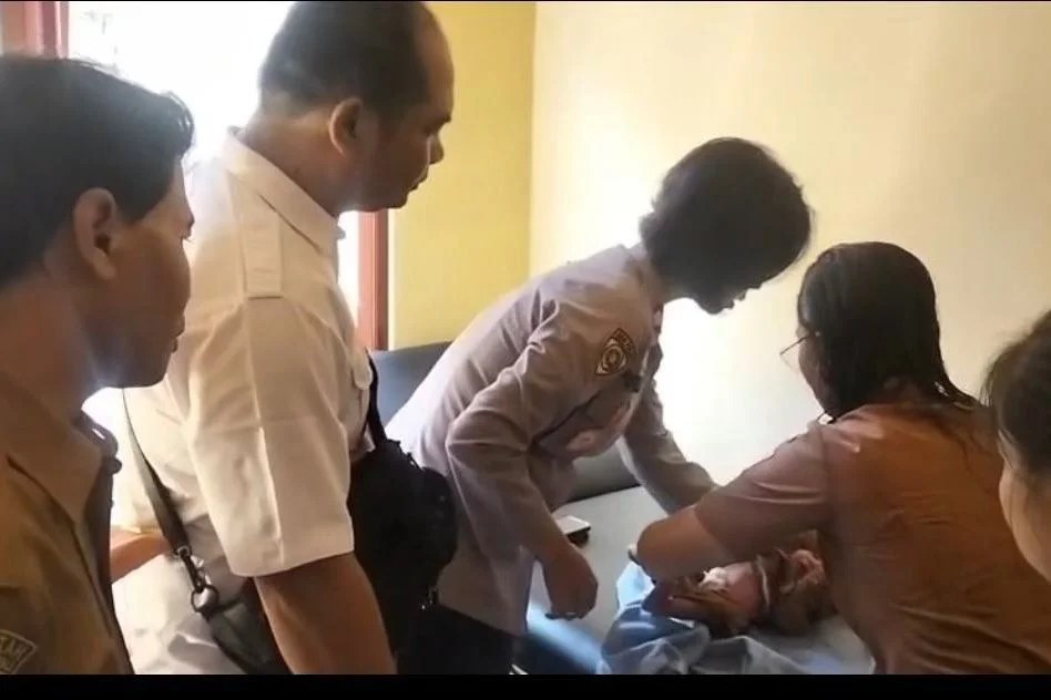 Petugas kepolisian saat mengamankan dan memastikan kondisi bayi laki-laki yang ditemukan di persawahan Desa Buruan, Gianyar.
