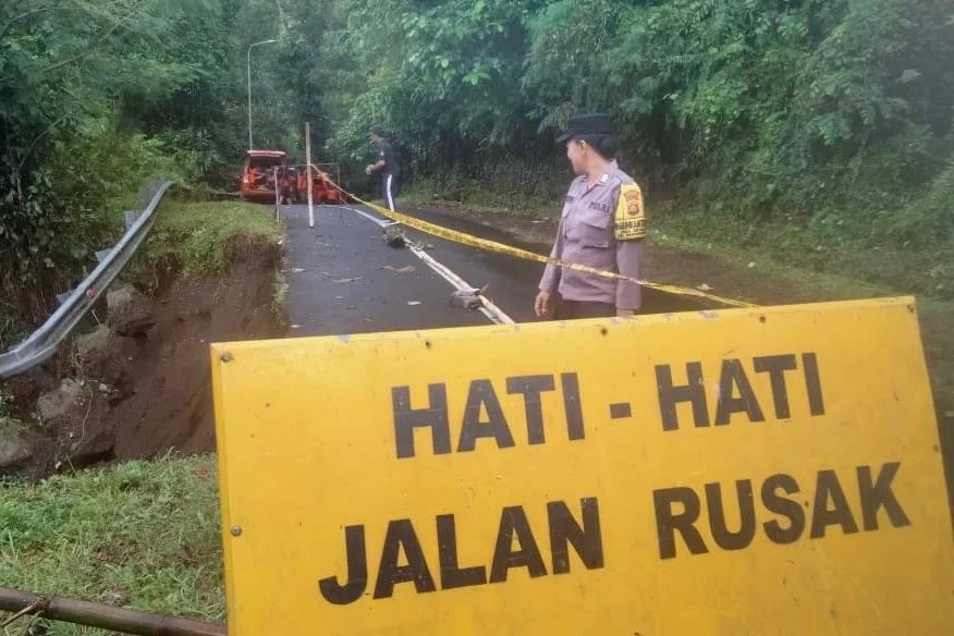 Bhabinkamtibmas Desa Getakan Bripka Ni Wayan Murniasih bersama petugas BPBD Klungkung saat memasang garis pembatas di bahu jalan yang longsor.