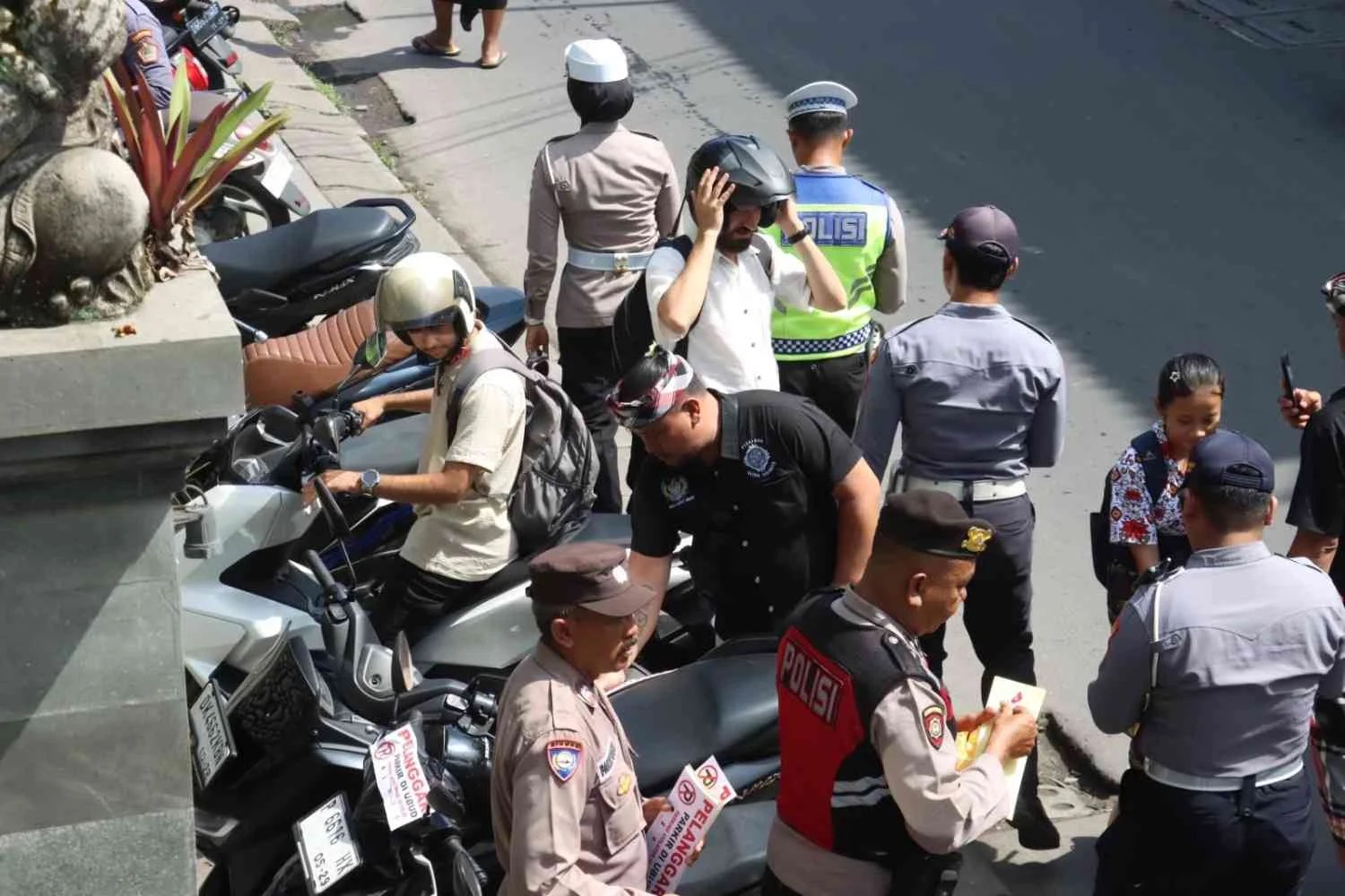Personel gabungan Polsek Ubud dan Dishub Gianyar saat menempelkan stiker teguran pada kendaraan yang parkir liar di badan jalan Raya Ubud.
