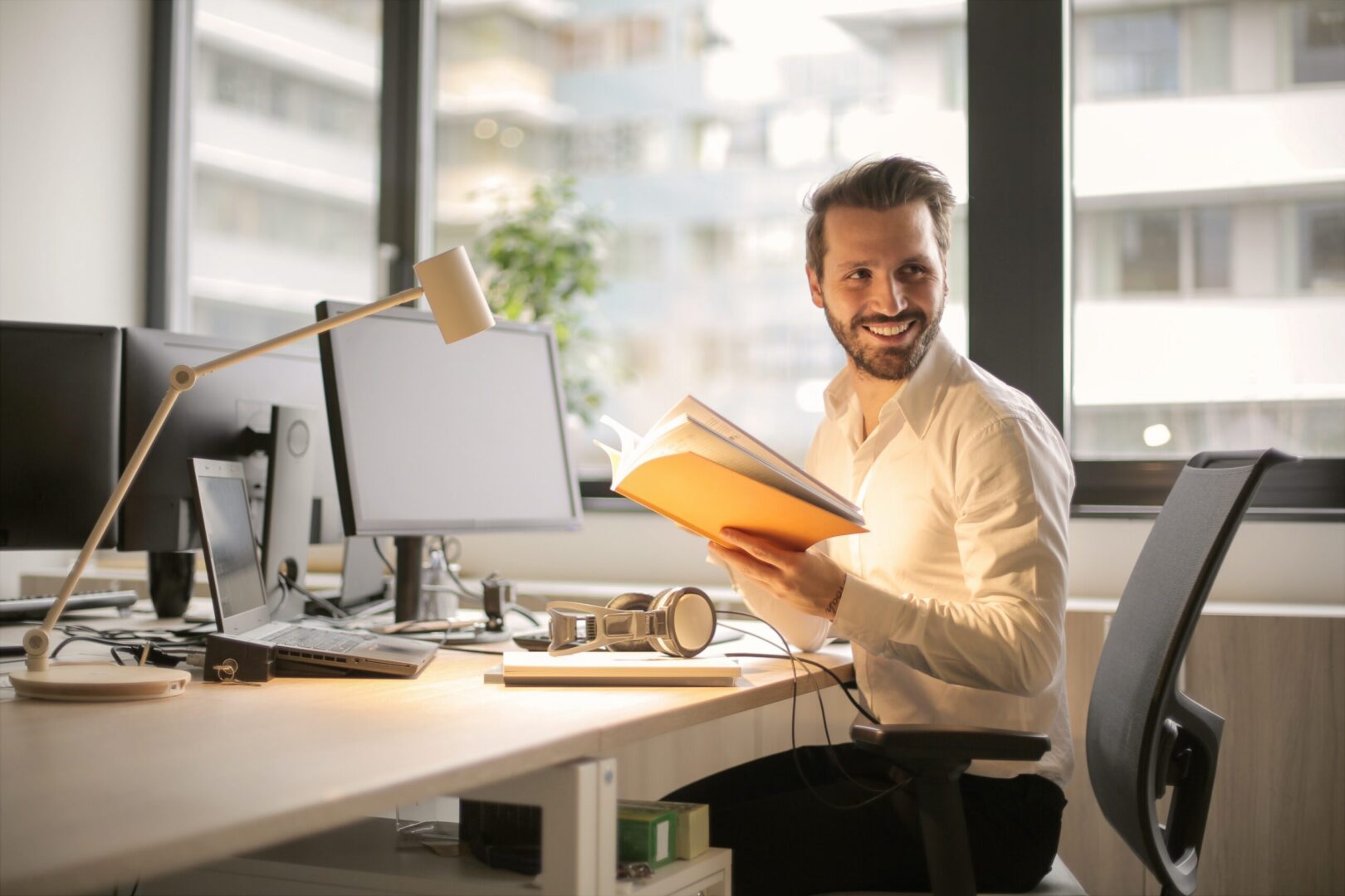 Smiling man reading book at office desk