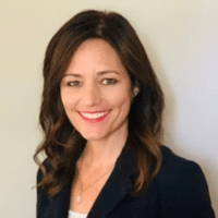 Smiling woman in dark blazer against neutral background