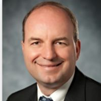 Professional headshot of smiling man in suit