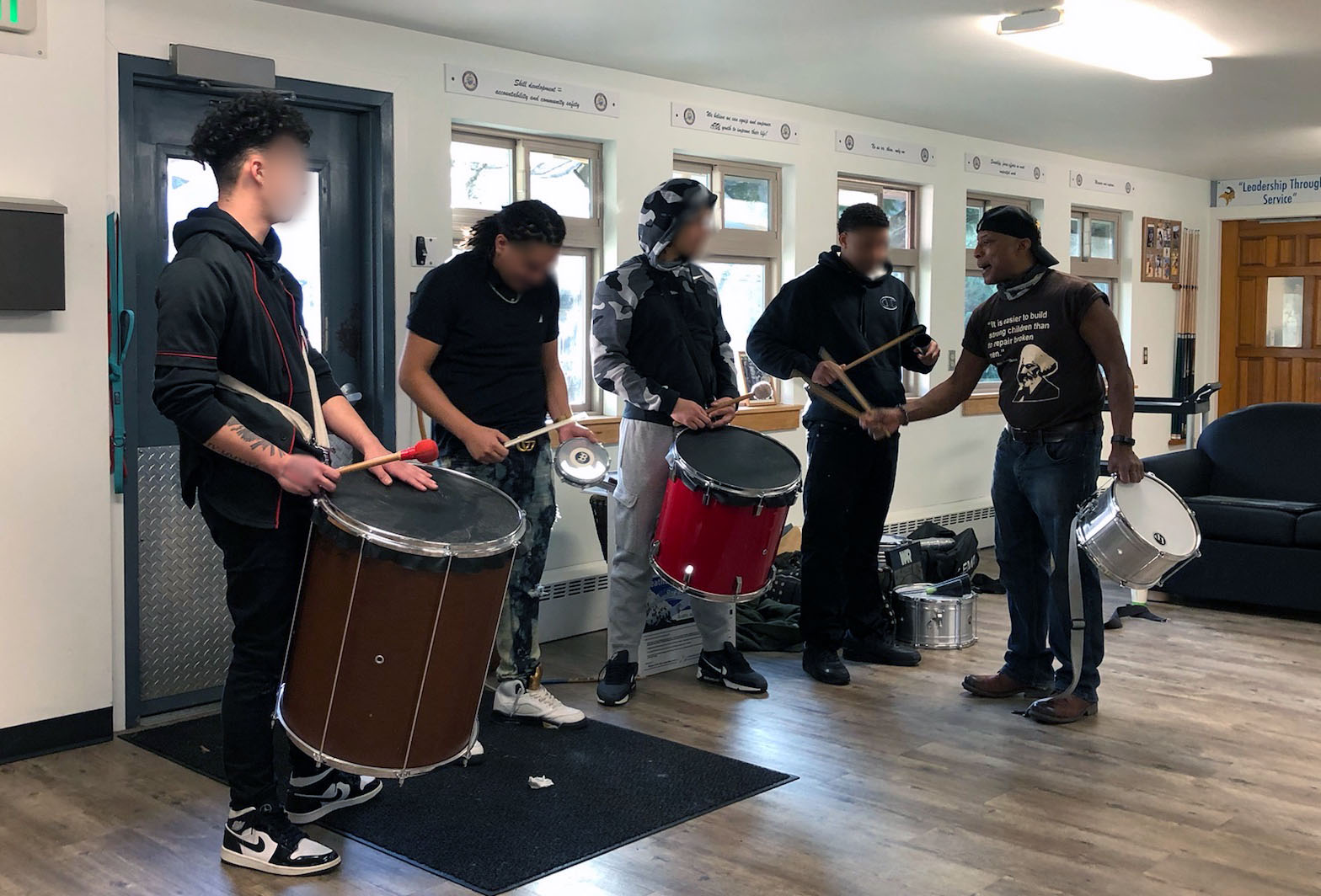 A man shows four young men how to play drums inside at Camp Florence