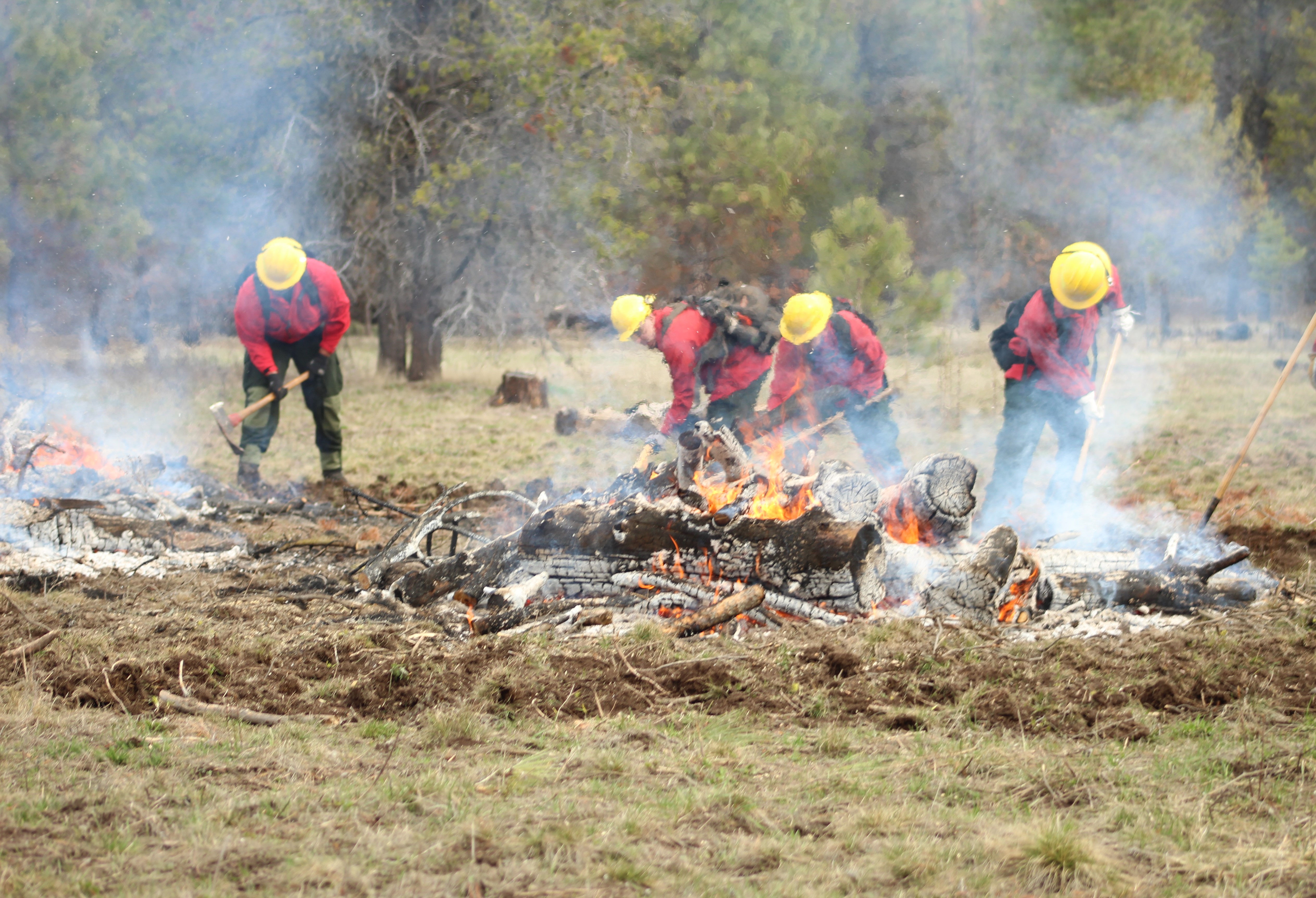 Firefighting students digging around a live fire outside