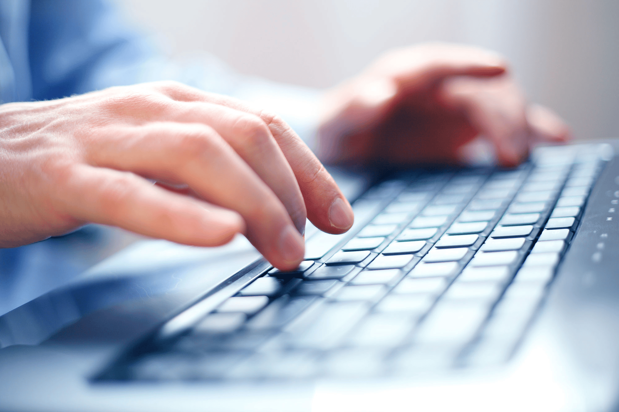 Hands typing on a laptop keyboard