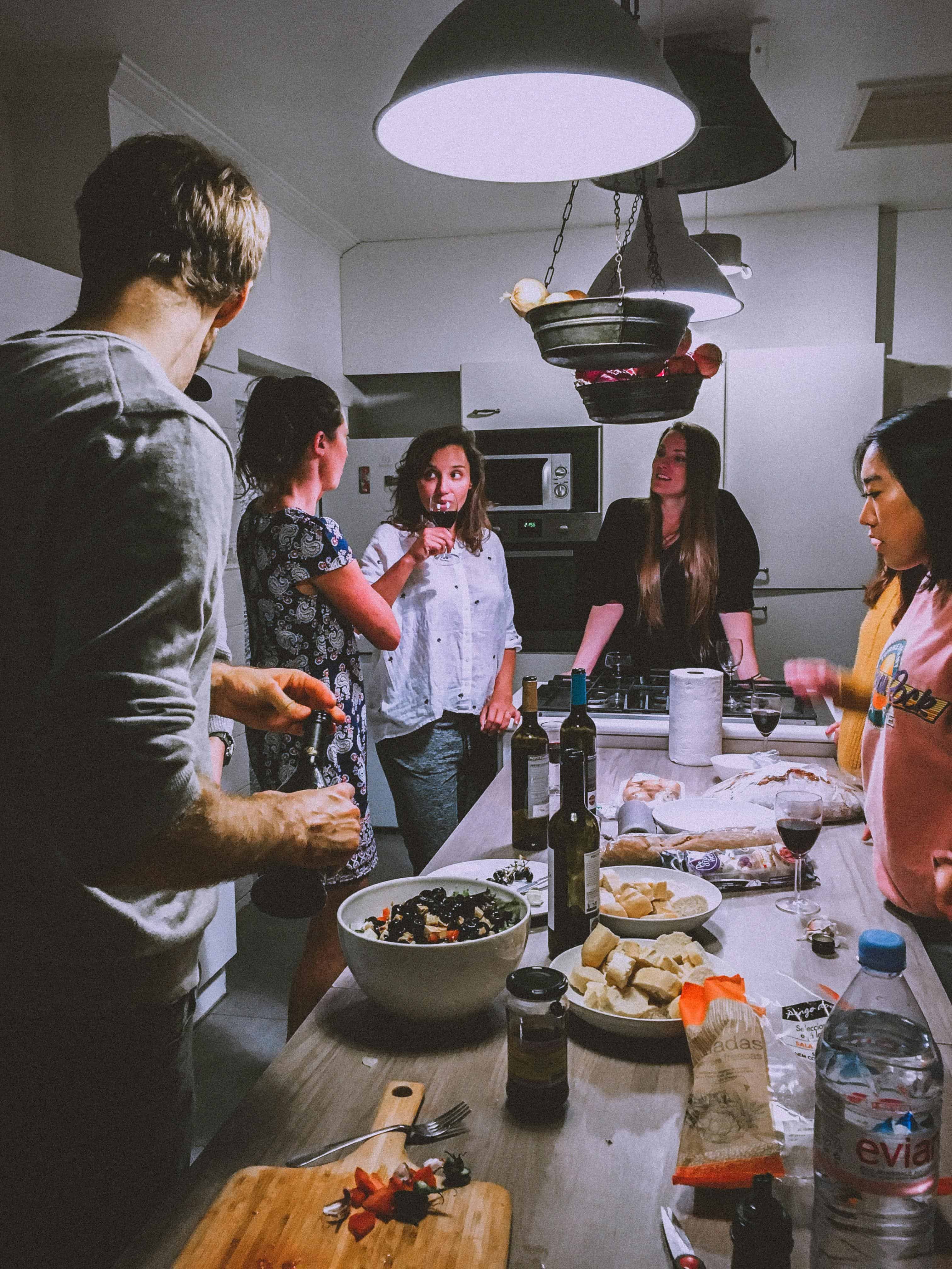 Group of friends enjoying wine tasting in a modern kitchen setting.