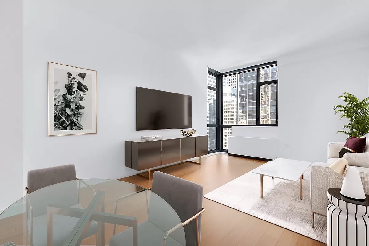 a modern living room with a corner window featuring an off-white couch, glass dining table set, tv and tv stand