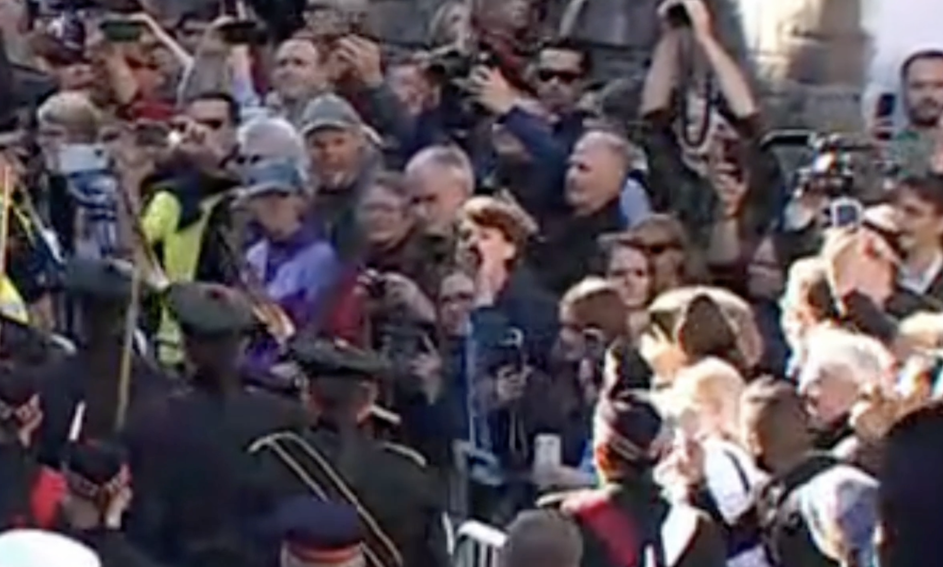 An observer gets yanked back by someone while yelling out loud during Queen Procession