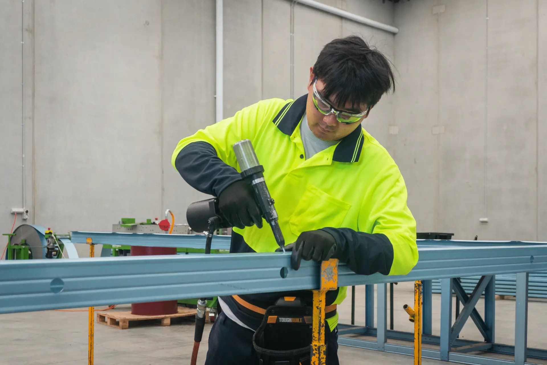 Worker in high-vis shirt fabricating lightweight steel framing in ISG Frames Pakenham Factory