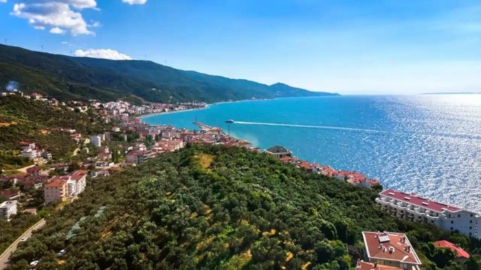 An aerial view of a coastal town on the Marmara Sea, with buildings spreading up a hill from the waterfront.