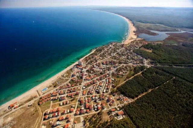 An aerial view of İğneada, Kırklareli, showing a long coastline, a town, a lake, and a large forest.