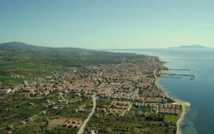 A high aerial view of Şarköy, a town in Tekirdağ, Turkey, situated on a narrow coastal plain between rolling green hills and the calm blue Sea of Marmara.