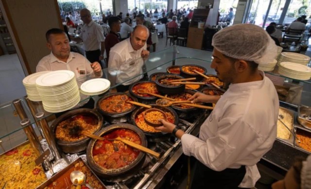 A traditional Turkish lokanta with stainless steel food trays displaying a variety of home-style dishes behind a glass counter.