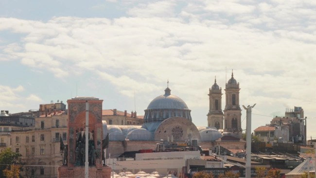 Taksim Square in Istanbul, showing the Republic Monument in the foreground and the Hagia Triada Greek Orthodox Church in the background.