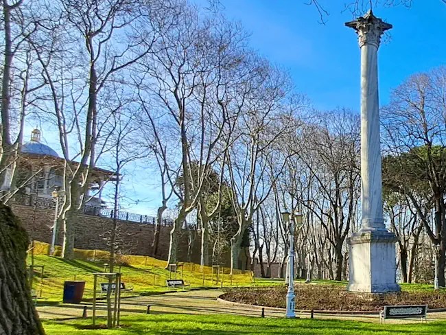 Gothic column and Topkapı Palace pavilion behind the walls in Gülhane Park, Istanbul.