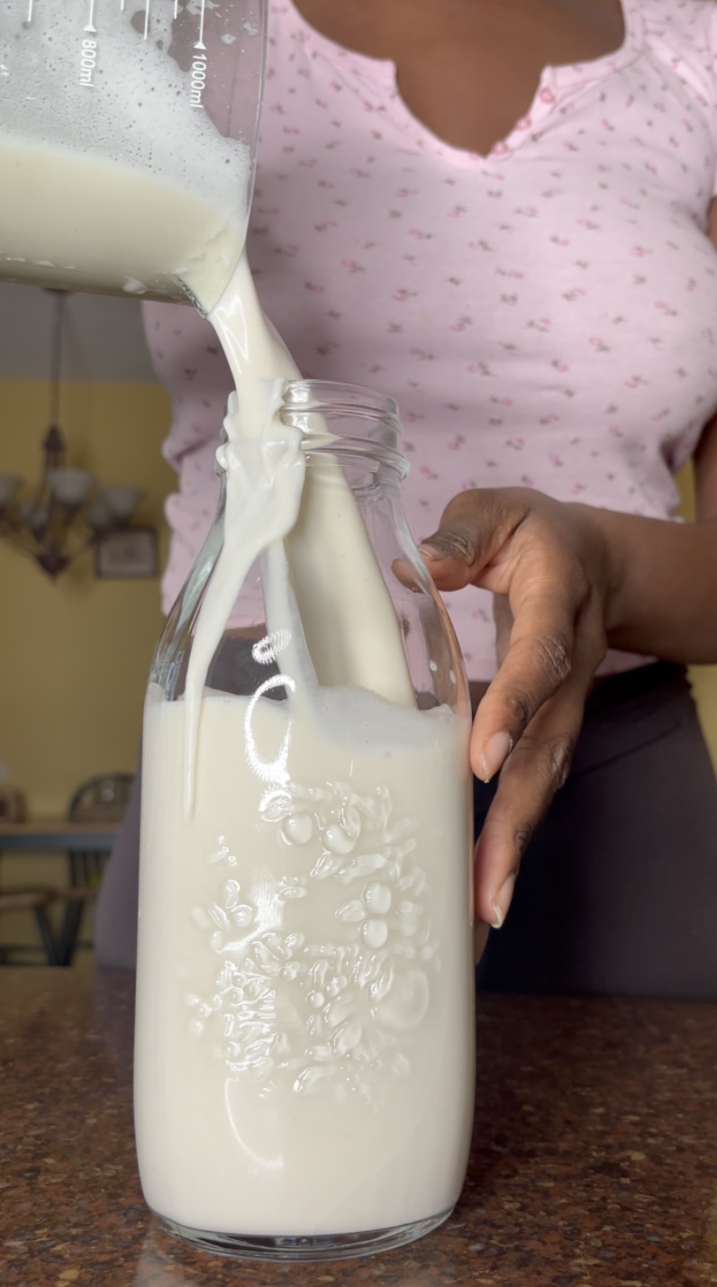 banana cashew milk being poured into a glass jar