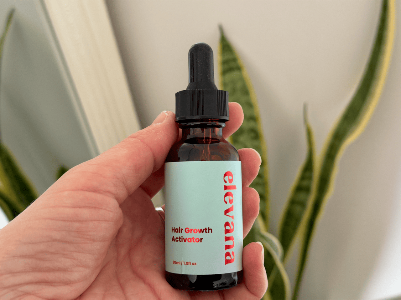 Holding a bottle of Elevate Hair Growth Activator Serum