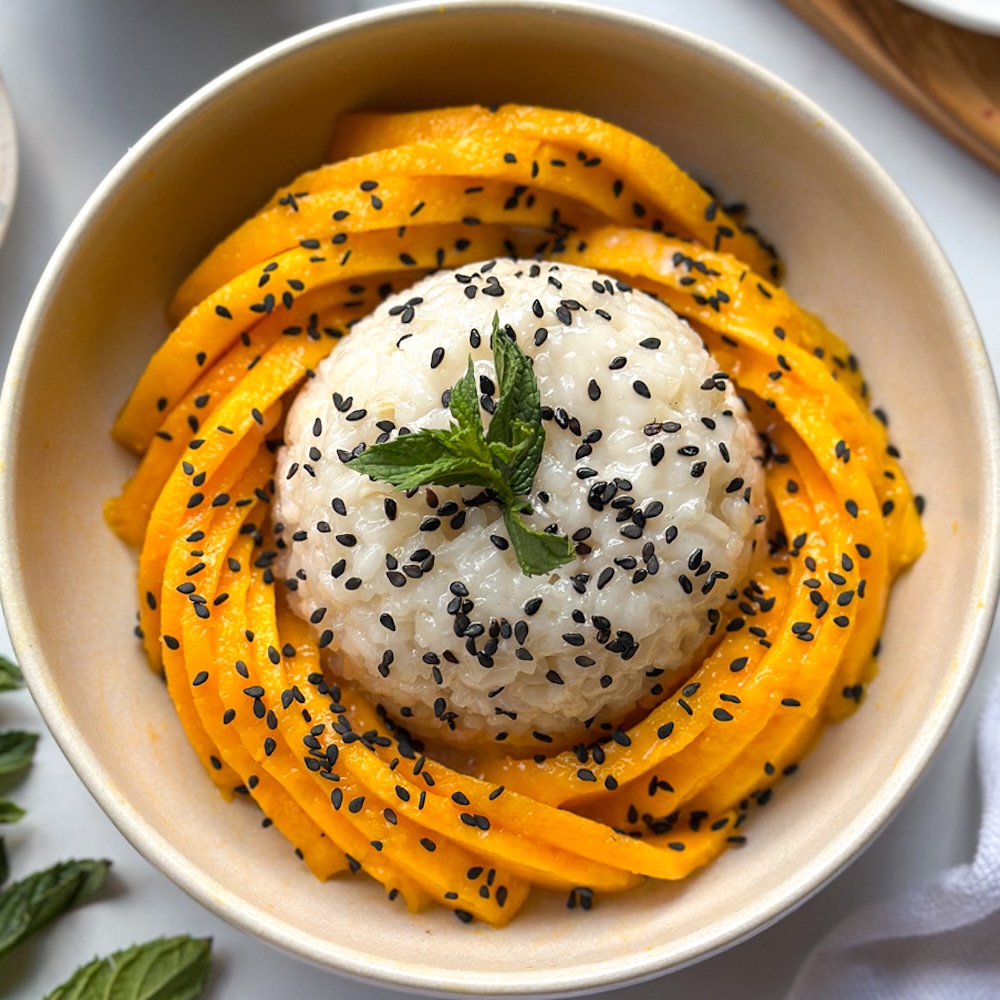 rice with sliced mango, black sesame seeds, and mint in a white bowl