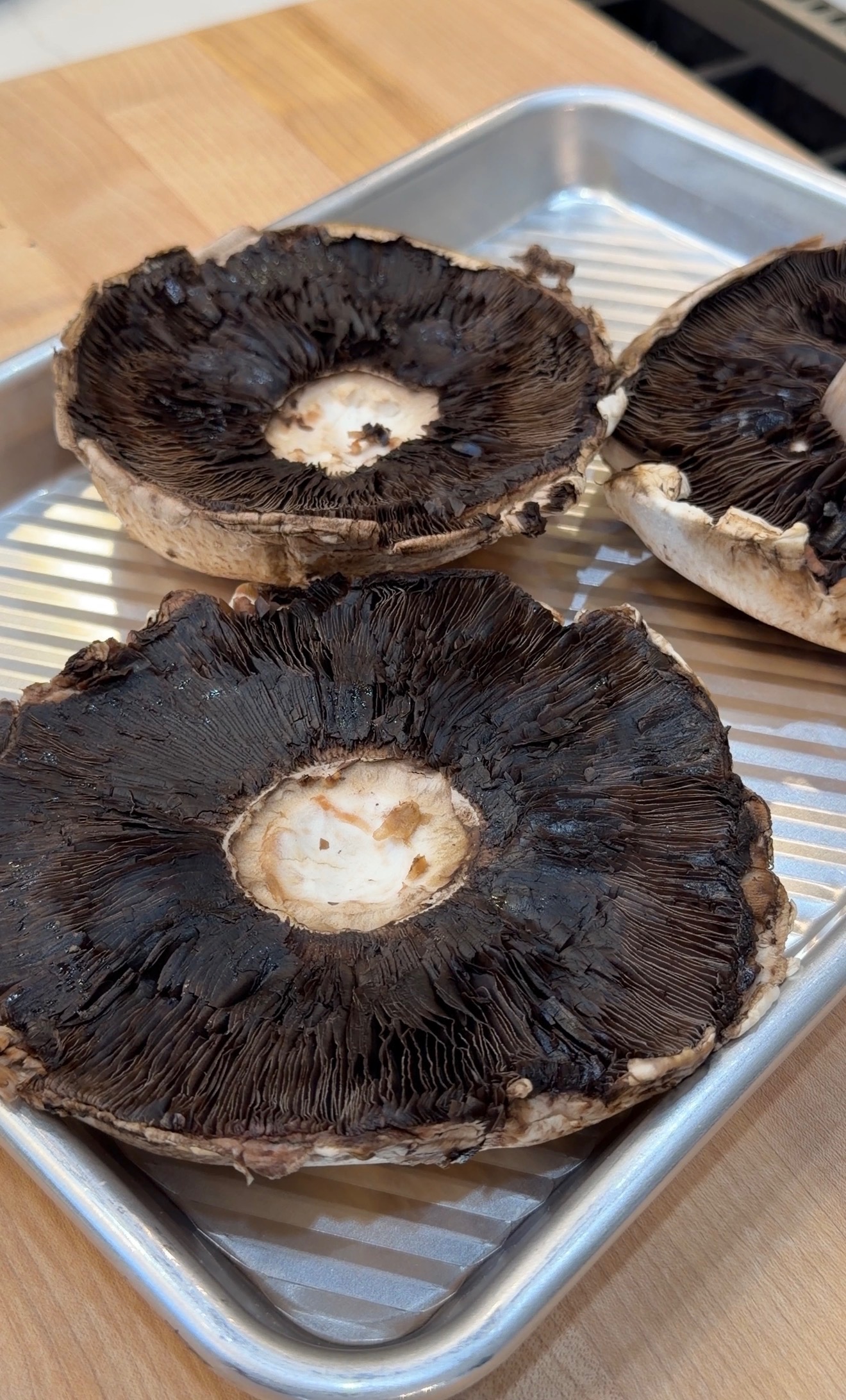 three portobello mushrooms on a metal sheet pan